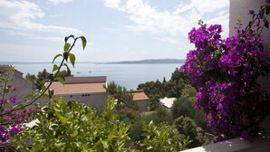 A balcony with a view of the sea and mountains, surrounded by greenery and purple flowers. - 5 Bedroom Villa, Pool, Sea Views, Baska Voda (Baska Voda)