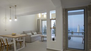 A modern living room with a sofa, dining table, and chairs. There is a balcony with a view of the sea. - Brand New Villa Ionion Theasis Armonia with sea view & private pool (Lefkada)