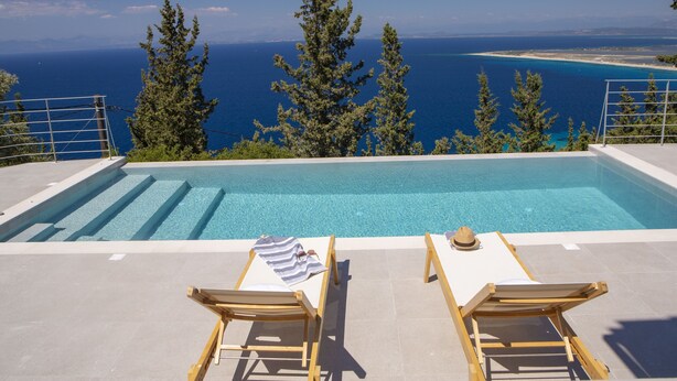 A poolside area with two sun loungers, a pool, and a view of the sea and coastline. - Brand New Villa Ionion Theasis Armonia with sea view & private pool (Lefkada)