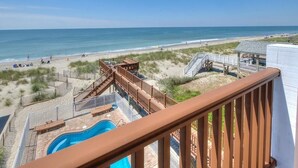 A beach view from a balcony with a pool, wooden deck, and beach access. - Oceanfront | Private Pool & Hot Tub | Adventures in Paradise (Oak Island)