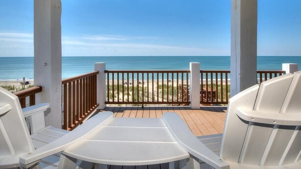 A covered deck with white chairs and a view of the beach and ocean. - Oceanfront | Private Pool & Hot Tub | Adventures in Paradise (Oak Island)