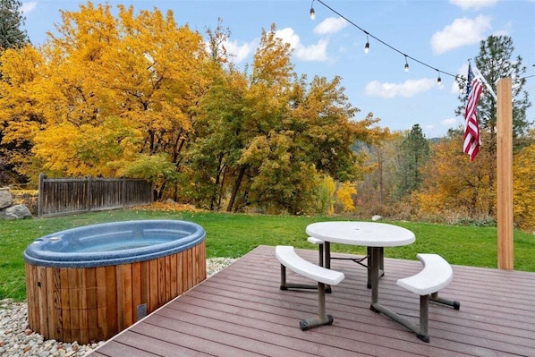 A hot tub, picnic table, and outdoor seating area on a wooden deck with a view of autumn trees. - Downtown Leavenworth Cottage w/ Hot Tub, Fireplace, BBQ (Leavenworth)