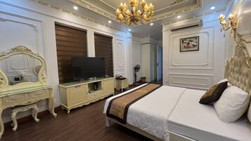 A bedroom with a large bed, a television on a cabinet, and a chandelier.