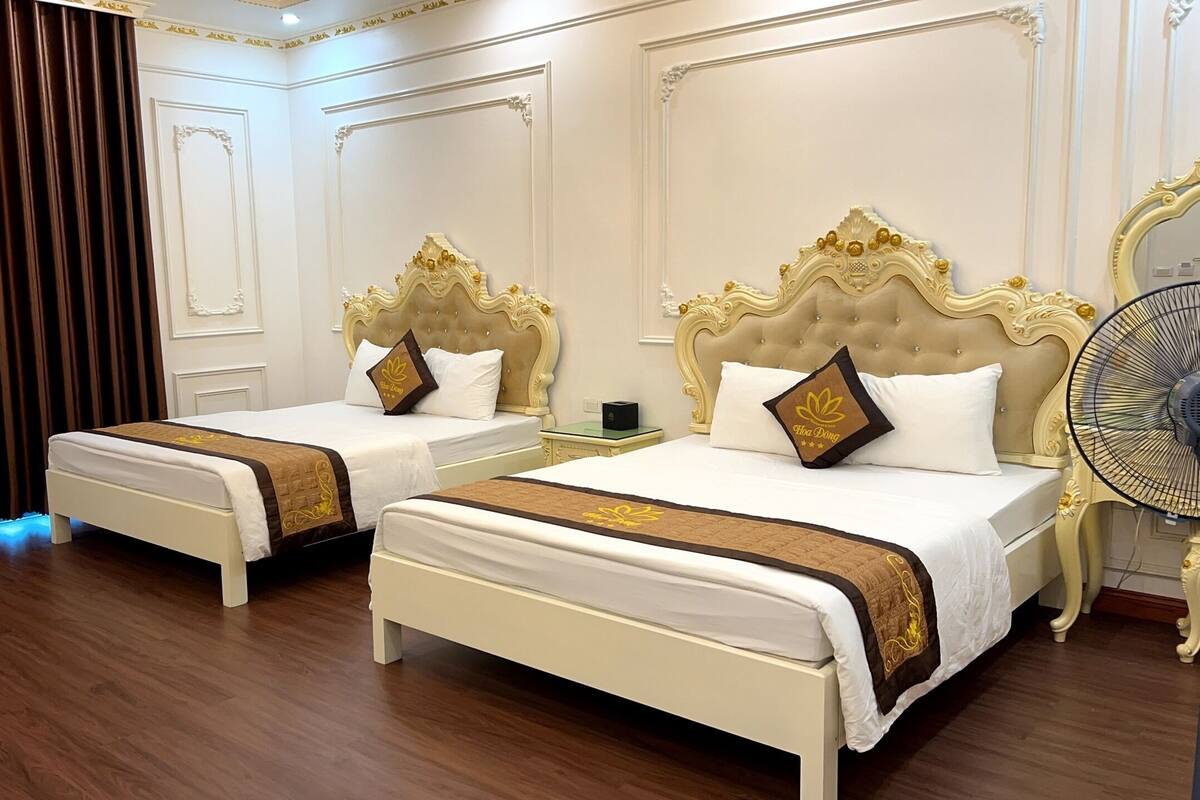 Habitación de hotel con dos camas, cada una con cabeceros ornamentados y almohadas a juego.