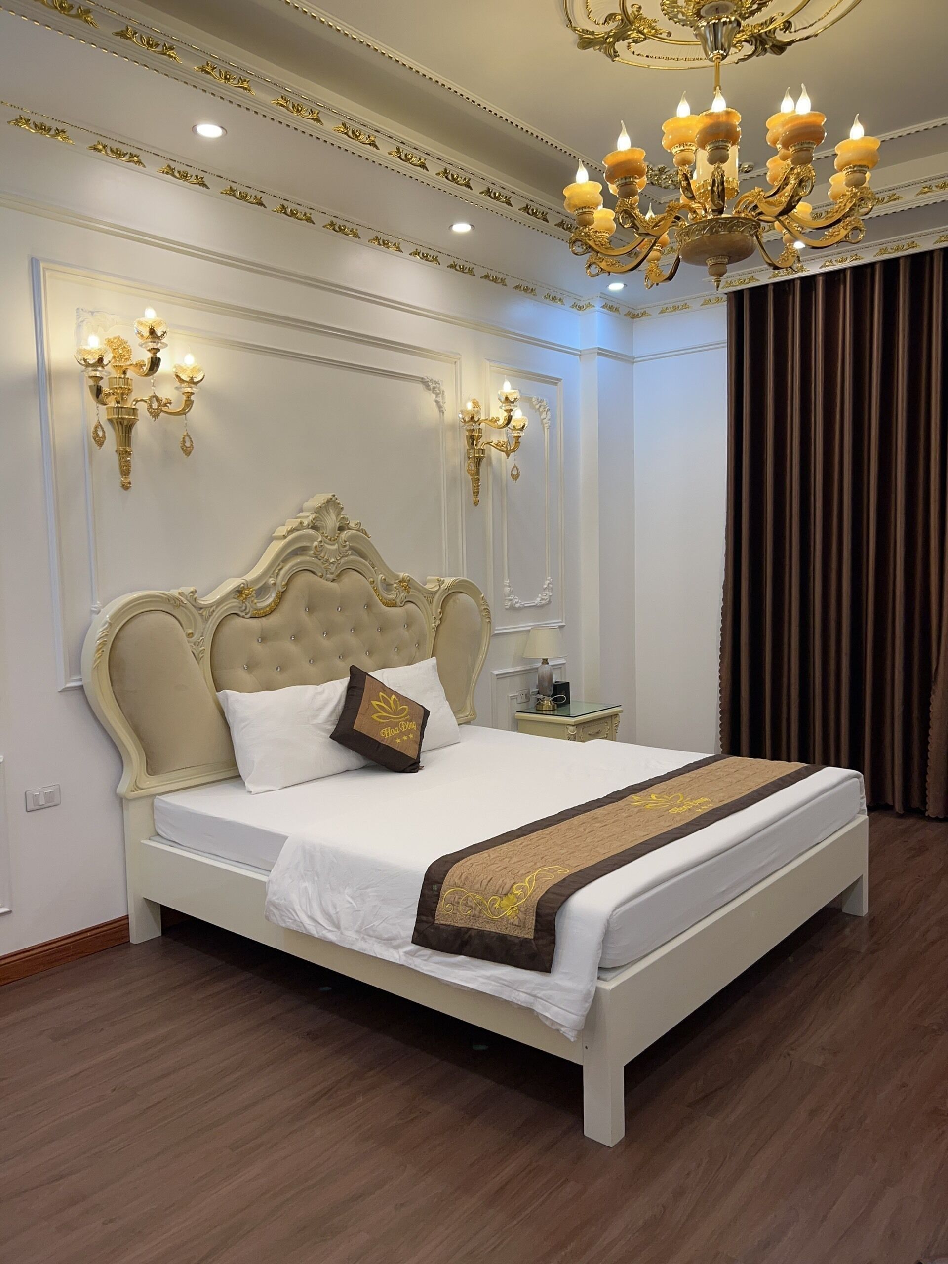 A large, ornate bed with a tufted headboard, white bedding, and a decorative throw.