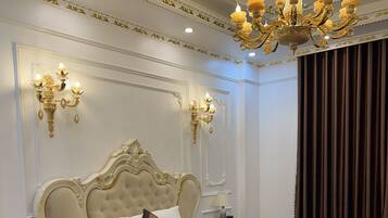 A large, ornate bed with a tufted headboard, white bedding, and a decorative throw.