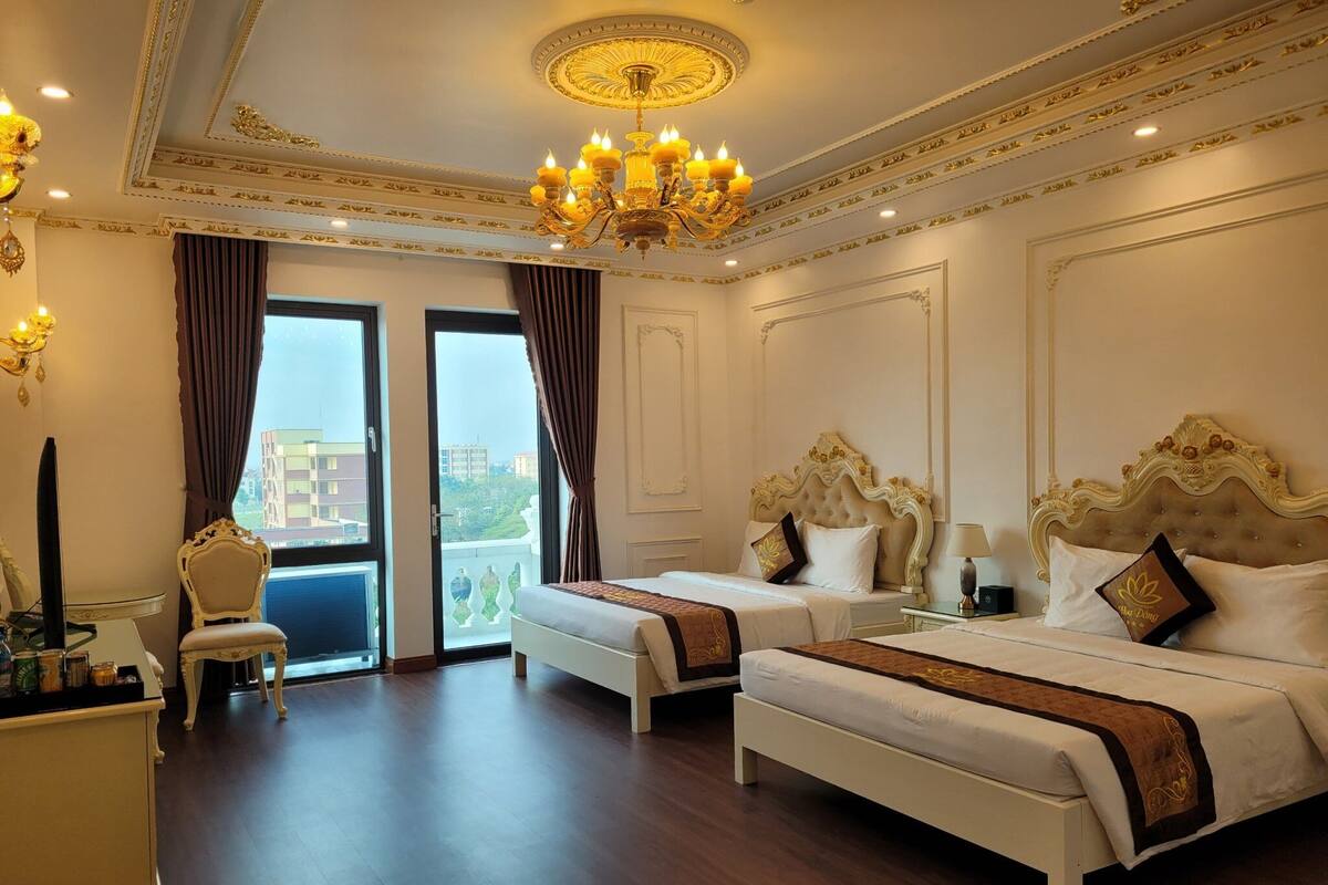 Habitación de hotel con dos camas, un candelabro y vistas a la ciudad.