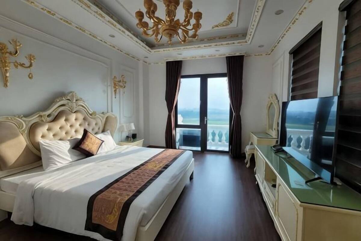 Habitación de hotel con una cama grande, televisión, escritorio y balcón con vistas.