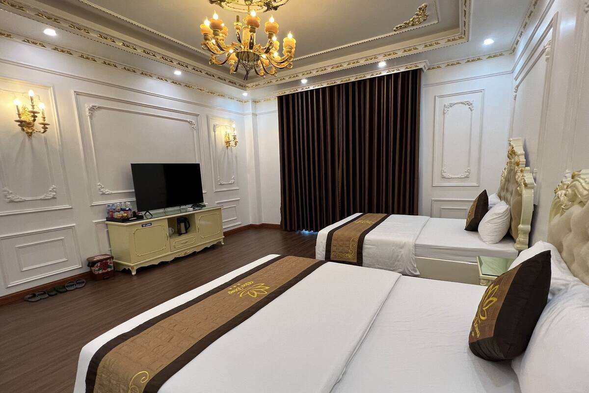 Una habitación de hotel con dos camas, televisor, minibar y candelabro.
