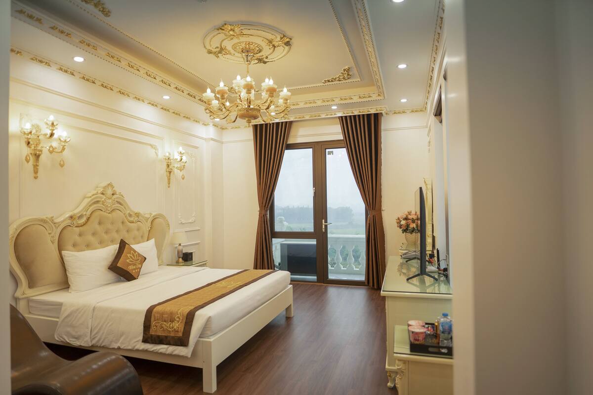 Habitación de hotel con una cama grande, una araña y vistas por la puerta.