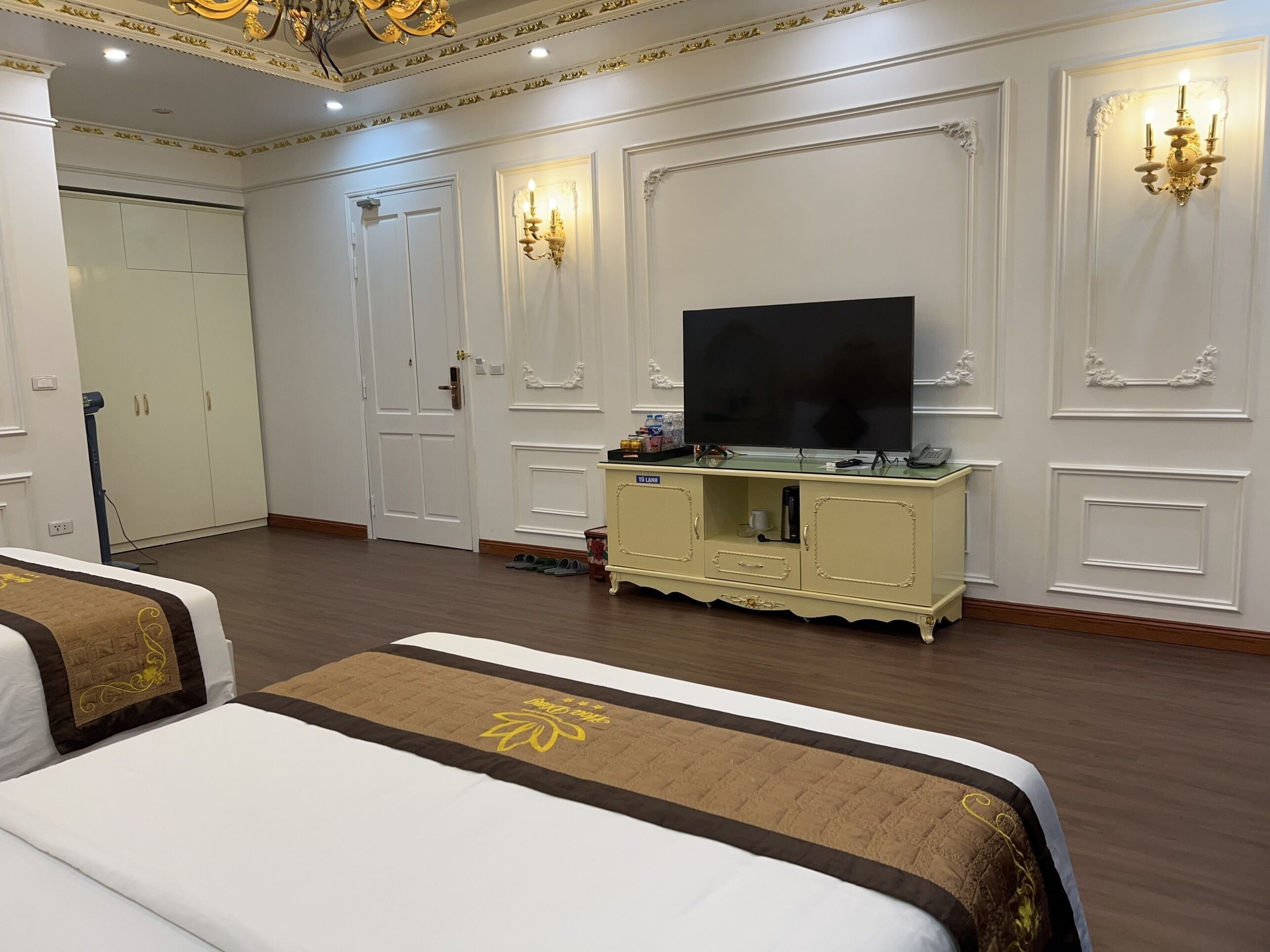 Une chambre d’hôtel avec deux lits, un téléviseur posé sur un meuble et une armoire.