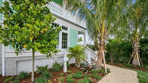 A house with a white exterior, a green door, and a gravel pathway leading to the entrance.