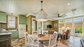 A kitchen with a dining area, wooden flooring, and a ceiling fan.