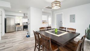 Una cocina moderna con electrodomésticos de acero inoxidable, un comedor con una gran mesa de madera y sillas, y una decoración minimalista.