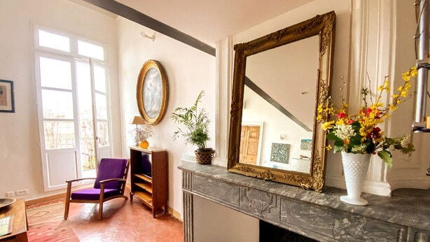 Een kamer met een open haard, een grote spiegel en een stoel.
