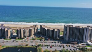 Een kusthotel met meerdere hoge gebouwen, een parkeerplaats en uitzicht op de oceaan.