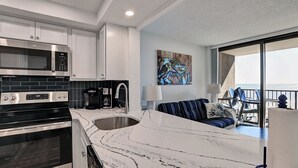 Una cocina moderna con una isla grande, un comedor con vistas y una sala de estar con balcón.