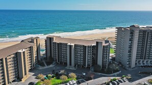 Un hotel de gran altura con varios pisos, estacionamiento y vista a la playa y al océano.