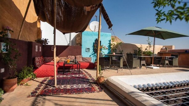 Une terrasse sur le toit, aménagée avec un espace salon, une table et un grand parasol.