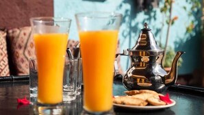 Une table avec deux verres de jus d’orange, une théière et une assiette de biscuits.