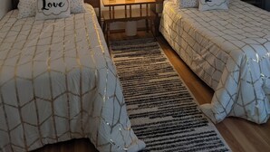 A hotel room with two beds, a nightstand, a lamp, and wall art.