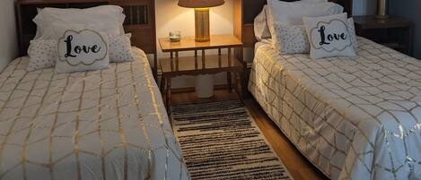 A hotel room with two beds, a nightstand, a lamp, and wall art.