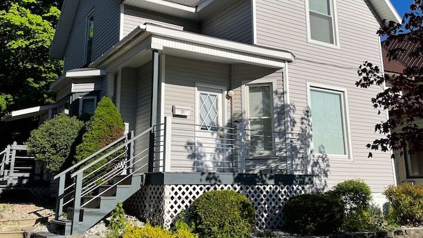 A two-story house with a front porch, a staircase, and a mailbox.