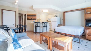 A compact hotel room with a sofa, a wooden table, a bed with a mattress label, a kitchenette, and a TV. - Amazing Copper Mountain Views, free wifi, free parking. (Copper Mountain)