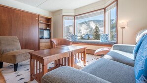 A cozy living room with a wooden dining table, grey sofas, and a large bay window offering a scenic view of mountains and a lake. - Amazing Copper Mountain Views, free wifi, free parking. (Copper Mountain)