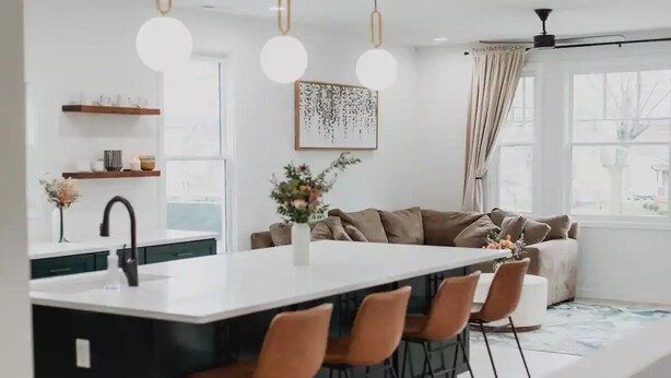 A modern kitchen with a central island, bar stools, and pendant lighting. - Modern Downtown Indy Apt - King Bed, Patio & Cute Flower Shop Below (Indianapolis)