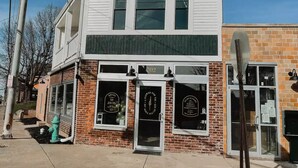 A two-story building with a brick facade and a white upper section. - Modern Downtown Indy Apt - King Bed, Patio & Cute Flower Shop Below (Indianapolis)