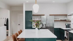 A modern kitchen with a central island, stainless steel appliances, and a hanging light fixture. - Modern Downtown Indy Apt - King Bed, Patio & Cute Flower Shop Below (Indianapolis)