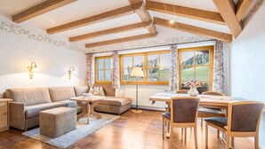 A room with a wooden ceiling, a sofa, a dining table with chairs, and large windows with curtains. - Holiday Apartment "Haus zur Vogelweide App 6" with Mountain View, Balconies & Wi-Fi (Dobbiaco)