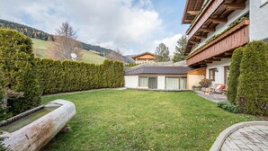 Une pelouse bien entretenue, un bateau en bois et un bâtiment doté d’un toit en pente et de balcons en bois.