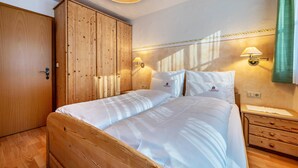 Un dormitorio con una cama de madera, dos mesitas de noche con lámparas, un armario y un aplique de pared.
