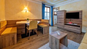 Una habitación con una mesa de comedor de madera, sillas, un sofá, un televisor y una lámpara.