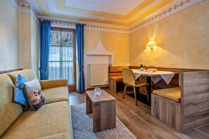 Una habitación acogedora con sofá, una mesita, comedor y ventana con cortinas.