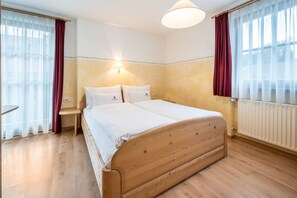 Un dormitorio con una cama de madera, una mesita de noche, una lámpara y una ventana con cortinas.