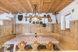 A wooden interior with a table set for dining, a chandelier, and various kitchen utensils on the wall.