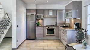 A modern kitchen with stainless steel appliances, a built-in oven, and a dining area with a table and chair.