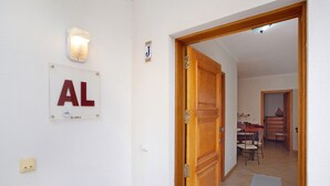 Un pasillo con una puerta, una lámpara y un letrero con las letras 'AL' y un número.