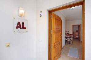 A hallway with a door, a light fixture, and a sign with the letters 'AL' and a number.