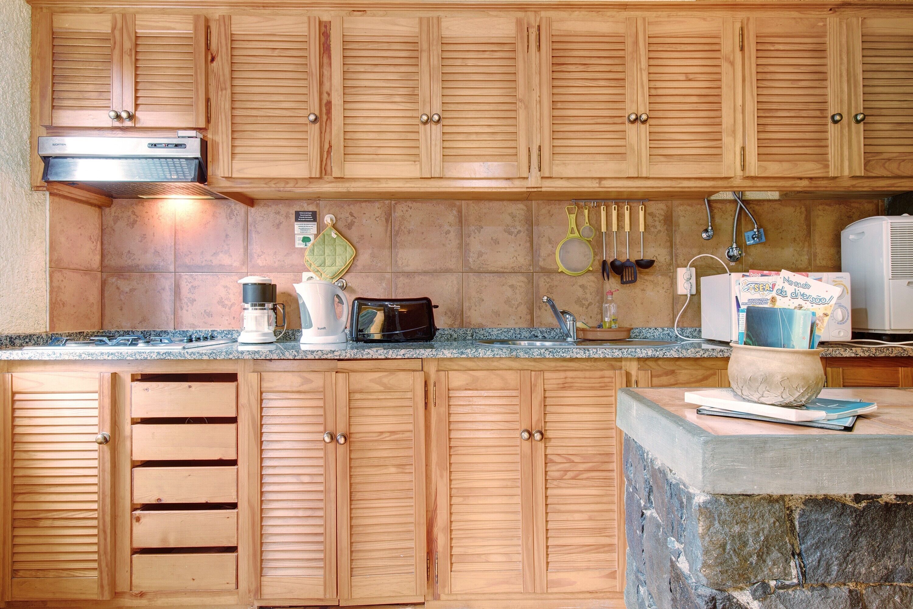 A kitchen with wooden cabinets, a built-in stove, a coffee maker, and various utensils on the countertop.