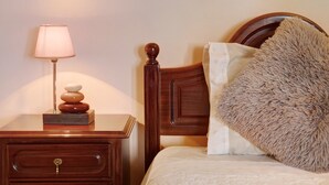Un lit bien fait, avec un oreiller moelleux, une lampe de chevet et une table de nuit en bois dotée d’un tiroir.