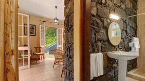 Une salle de bain avec un mur en pierre, un lavabo blanc et un miroir.
