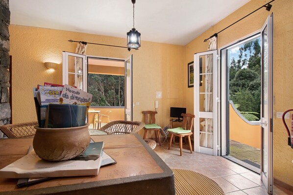 A room with a dining table, chairs, a large window, and a door leading outside.