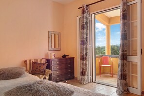 A bedroom with a bed, dresser, and a balcony with a chair.