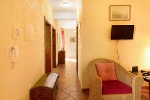 Un pasillo con un sofá de mimbre, un televisor y un teléfono.
