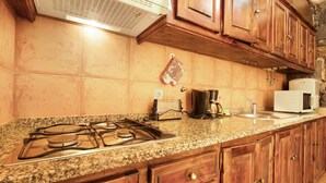 Eine Küche mit Granit-Arbeitsplatten, Holzschränken, einem Gasherd, einer Kaffeemaschine und einer Mikrowelle.