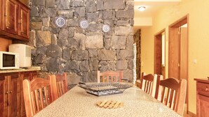 Ein Essbereich mit Steinwand, Holzsesseln, einem Granittisch und einer Mikrowelle auf der Arbeitsfläche.